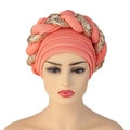 Close-up of coral pink turban with detailed golden sequin braided crown design - Watermelon red