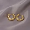 Thick gold hoop earrings with irregular hammered texture on light grey silk background - Irregular Ripple / E-054---Gold