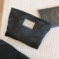 Dettaglio trousse nera in tessuto jacquard con ricami a fiocco e etichetta testuale - Fiocco Nero