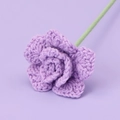 Macro shot of a hand-knitted purple rose flower with detailed crochet petals and green stem - Purple