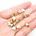Makroaufnahme von 15 goldenen Herzperlen aus CCB für DIY-Schmuck auf einer Handfläche - Herz Zwischenperlen Gold 6x7mm (2000 Stk)