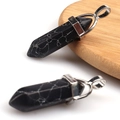 Two black hexagonal crystal pendants with silver clasps on a round wooden base - Synthetic Black Turquoise
