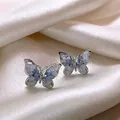 Nahaufnahme der Schmetterlings-Ohrringe mit blauen Kristallen auf Seidenhintergrund - Blau Transparent Strass Schmetterling Ohrstecker (10# Silbernadel-Silber)