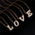 Detail of four gold necklaces with sparkling zircon pave letters spelling LOVE on black background - Letter Y / Gold