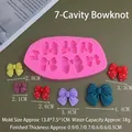 Detail view of pink silicone mold with seven different bow shapes and finished resin samples - 7-Hole Bowknot