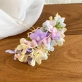 Detail of delicate handmade silk flowers on a golden wavy metal hairpin for wedding - Colorful