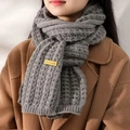 Close-up of gray knit scarf featuring a yellow handmade label on thick waffle texture - Grey Label Scarf