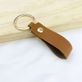 Minimalist brown PU leather keychain featuring a golden metal ring and rivet detail - No.7 Caramel
