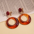 Détail macro de boucles d'oreilles clips en résine ambre avec motif marbré rétro et vis or - Style Clip à Spirale / Marron