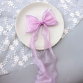 Close-up of a large pink organza ribbon bow hairclip on white lace and floral decor - 1232 Pink Purple Mesh (with Clip)