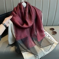 Burgundy silk scarf with gold sparkles and black mesh trim draped on beige knitwear - Burgundy