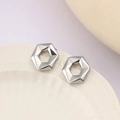 Dettaglio degli orecchini a perno esagonali in argento su un piatto di ceramica - Argento