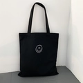 Close-up of minimalist black canvas tote bag with white line smiley face and sturdy handles - Black Smile