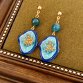 Close-up of vintage gold flower earrings with blue enamel and teal beads on dark fabric - Long Style / Gold-Blue