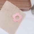 Gros plan d'une pince à cheveux fleur rose avec base en métal sur tissu de lin rustique - Rose Clair