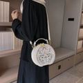 Detailed embroidery on white round crossbody bag with adjustable strap worn by model - Milky White