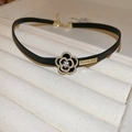 Detalle de gargantilla de cuero floral negro con perla y diamantes en bandeja de terciopelo - Collar de cuero con flores negras
