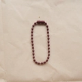 Detailed top view of a 2.4mm brown metal bead chain connector on crinkled paper - Coffee