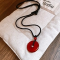 Detail of red agate ring pendant with black cord necklace on a cream fabric pouch - 18# Black Red Necklace