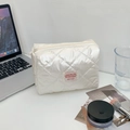 Detailansicht der weißen gesteppten Kosmetiktasche mit rosa Etikett und Perlglanz - Weiß