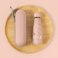 Compact light pink capsule umbrella with matching hard shell case on a wooden tray - 6-Rib Mini Vinyl Thickened + Capsule Box / Grapefruit Pink
