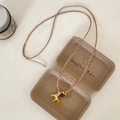 Detail einer Vintage-Halskette mit goldenem Pferd und Hufeisen-Anhänger in einer braunen Box - Glänzend goldenes Pferd mit roten Perlen und Hufeisenquaste / Halskette - Gold - Weiß