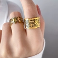 Makroaufnahme goldener Ringe mit Lebkuchenmann-Motiv und Gravuren im Graffiti-Stil - US 6 / Künstler Graffiti Breitband