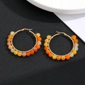 Detail of round hoop earrings with golden wire wrap and gradient colored beads - Orange Beads