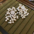 Detailed macro view of handmade white pearl flower earrings on dark green velvet - Silver Earring Post-White