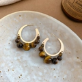 Macro shot of gold C-shaped earrings set with five tiger eye stones on ceramic plate - 40# Silver Earring Post - Gold Coffee