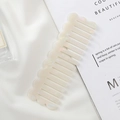 Detail of a beige acetate hair comb with marble texture on elegant white silk background - Mermaid Color