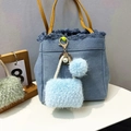 Detail of blue denim mini bag keychain with yellow leather handle and fuzzy plush charms - Sky Blue