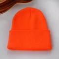 Détail macro du bonnet en tricot orange vif avec une texture côtelée épaisse et chaude - Rouge Orangé