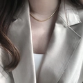 Elegant 18K gold-plated flat snake chain necklace worn on a beige blazer collar - Gold