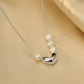 Silver heart and pearl pendant necklace displayed on soft gold silk fabric background - Necklace - Silver