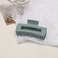 Close-up of matte grey-green rectangular hair claw clip on white textured paper - Cube / Milky Blue