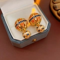 Macro detail of gold-plated double-ball earrings with colorful zircon inlay in a jewelry box - Gold