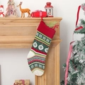 Gestrickter Weihnachtsstrumpf mit Schneeflocken und Pompons an einem Holzkamin hängend - Schneeflocke