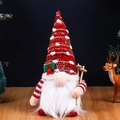 Christmas gnome plush with red knitted hat, white beard, and wooden ski poles on table - Skiing Glowing Gnome Red