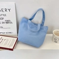 Détail d'un sac en toile bleu clair avec des anses solides sur une étagère - Haut Ouvert Minimaliste / Bleu Eau
