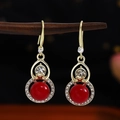 Detail of red beaded earrings with white rhinestones hanging on a wooden stand - Gold Red White Rhinestone
