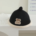 Detail der Strickmütze für Babys mit süßem Bären-Aufnäher und weicher schwarz-weißer Textur - Bär Patch - Schwarz