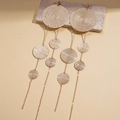 Close-up of textured golden metal earrings with layered round discs and long tassels - Gold / Gold
