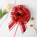 Detail of red ribbon gift bow with sheer edges and metallic finish for festive decor - Red