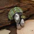 Spilla a fungo vintage con strass verdi e gialli su una superficie in legno naturale - Verde