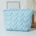 Close-up of light blue quilted cosmetic bag with heart pattern and zipper detail - Blue