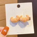 Close-up of cute croissant-shaped hair clip on a white tag being held by hand - Single Croissant