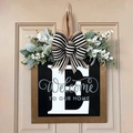 Letter E wooden door hanger with black base and artificial greenery and white flowers - Letter E