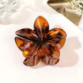 Macro detail of amber tortoiseshell floral hair claw clip made of translucent resin material - Amber Brown