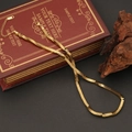 Dettaglio di una collana a maglie quadrate dorate su un libro rosso vintage e legno - Stile Piccolo Cubo (3#)